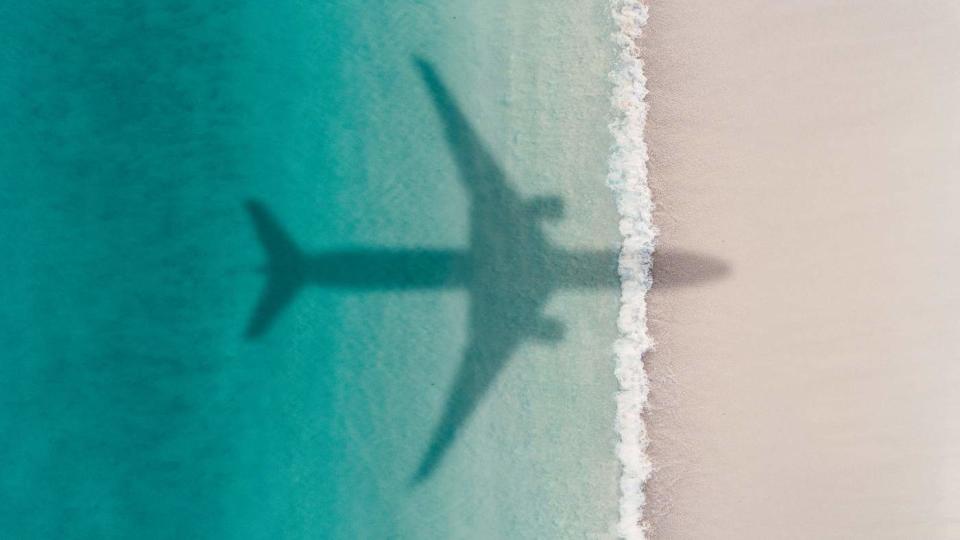 Aerial photograph showing the shadow of an airplane flying over an idyllic beach