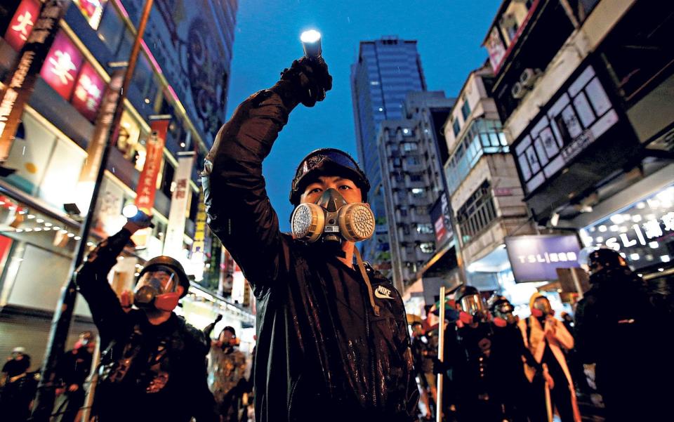 Demonstrators aim their flashlights towards riot police as they are chased through the streets of Hong Kong during a protest two years ago - Willy Kurniawan/Reuters