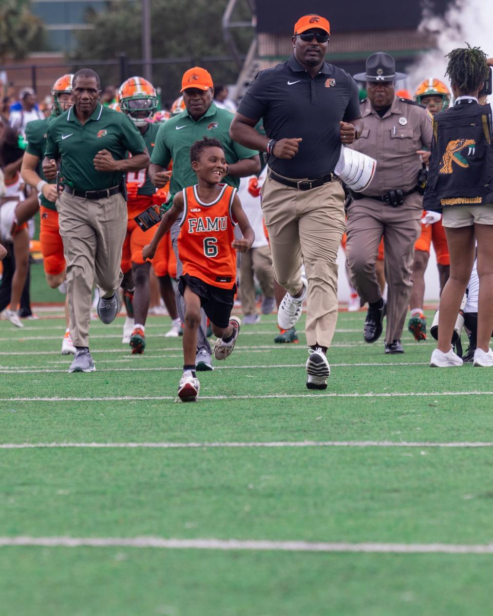 Florida A&M Rattlers head coach Willie Simmons and son, Champ, leads the football team out ahead of a game against the West Florida Argonauts at Ken Riley Field at Bragg Memorial Stadium in Tallahassee, Florida, Saturday, Sept. 16, 2023