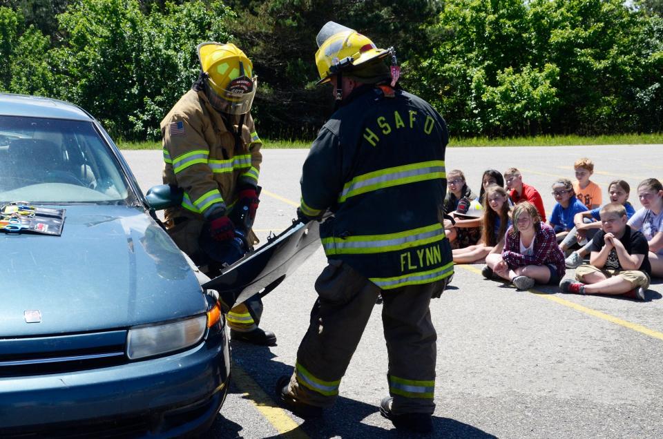 Area firefighters demonstrate how to use the Jaws of Life on a car door for local students at North Central Michigan College.