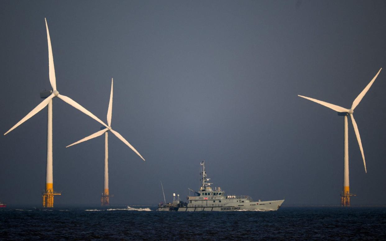 UK Border Force Cutter HMC Seeker passes wind turbines off the east coast - DANIEL LEAL/AFP