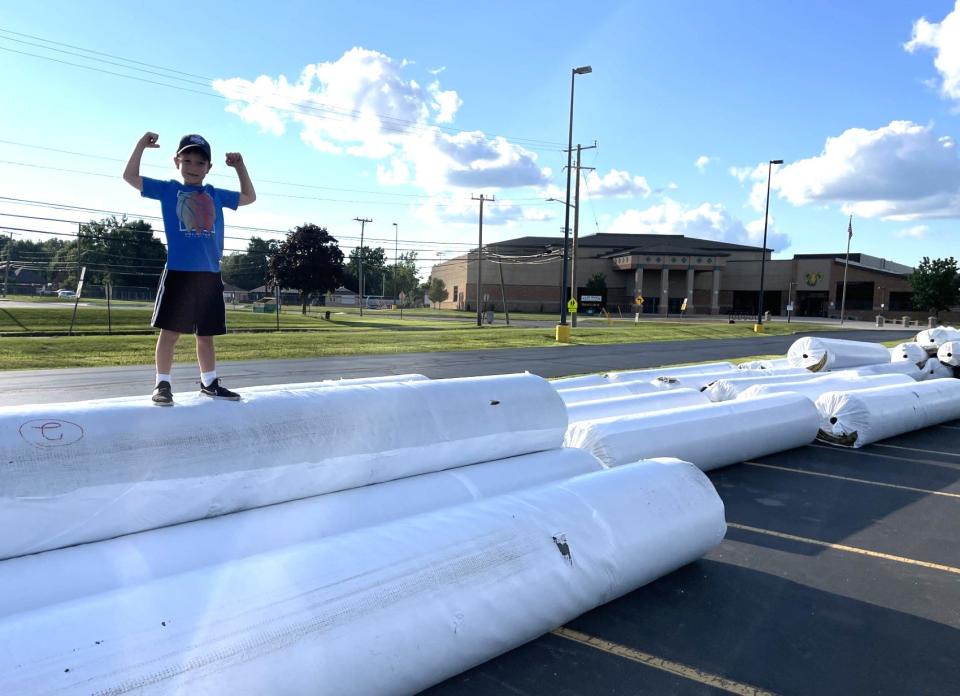 Brady Reaume, the 6-year-old son of Flat Rock football coach Buck Reeaume, stands on the bundles of artificial turf scheduled to be installed on Flat Rock's football field.