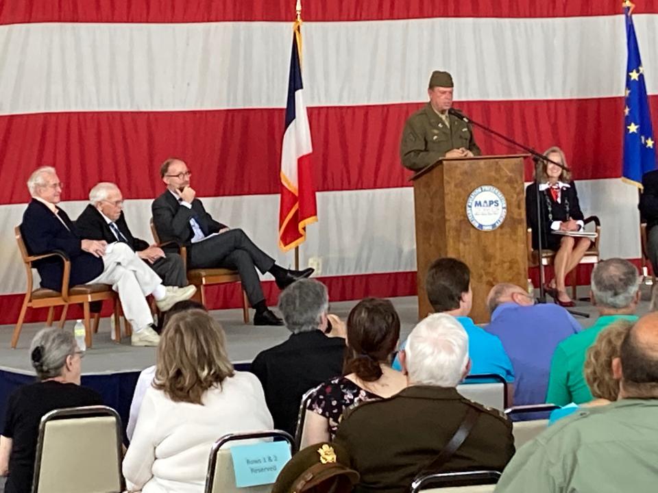 Eric P. Montgomery, who helped secure the French Legion of Honor for Walter B. Stitt and Leonard Giorgio, speaks during a program Saturday at the MAPS Air Museum. On stage watching are Stitt, far left, Giorgio and Yannick Tagand, consul general of France to the Midwest.