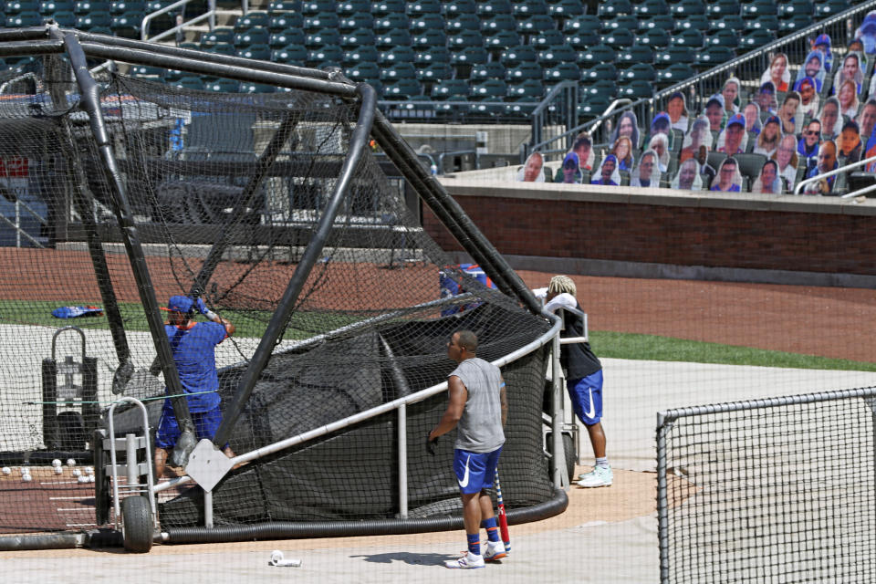 Carboard cutouts of fans are seen in the stands as members of the New York Mets take batting practice during a summer training camp workout at Citi Field, Thursday, July 16, 2020, in New York. Melky Cabrera is in the cage, left, with Yoenis Cespedes, center, and starting pitcher Marcus Stroman watching. (AP Photo/Kathy Willens)