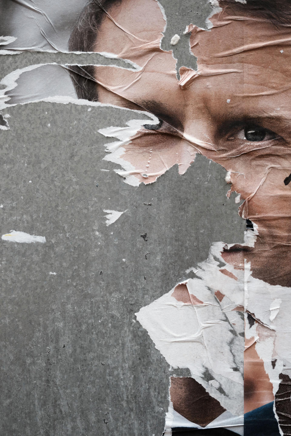 Torn presidential campaign poster of French President and centrist candidate for reelection Emmanuel Macron is displayed in Paris, Wednesday, April 13, 2022. France will vote on Sunday April 24 in the second round of the presidential election. (AP Photo/Thibault Camus)