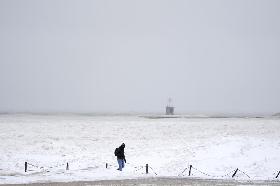 A lone man walks along a frozen section of North Ave. beach on Lake Michigan north of downtown Chicago Tuesday, Jan. 26, 2021. A major winter storm dumped more than a foot of snow on parts of the middle of the country stretching from central Kansas northeast to Chicago and southern Michigan.(AP Photo/Charles Rex Arbogast)