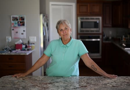 Janet Putrah, a retired university IT supervisor, poses for a photo in her home in Mankato