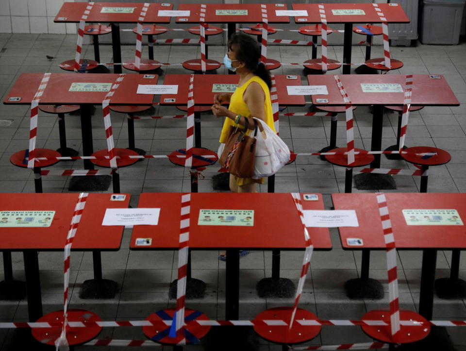 A woman walks between rows of taped up tables at a food centre as dining-in is restricted to curb the coronavirus disease (COVID-19) outbreak in Singapore May 17, 2021.   REUTERS/Edgar Su