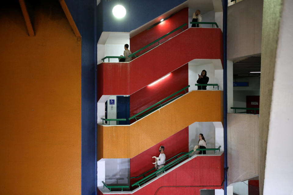 Actors from the Mystorin Theatre Ensemble, and a passerby, walk down the stairs during the group's show "Seven," at the Central Bus Station on Dec. 27, 2018. (Photo: Corinna Kern/Reuters)