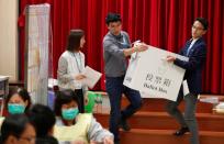 Polling officials carry a ballot box to count the votes of the Hong Kong council elections, in a polling station in Hong Kong