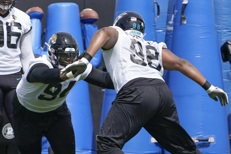 Jacksonville Jaguars defensive tackle Folorunso Fatukasi, left, performs a drill with defensive end Jeremiah Ledbetter (98) in an NFL football practice, Monday, May 23, 2022, in Jacksonville, Fla. (AP Photo/John Raoux)