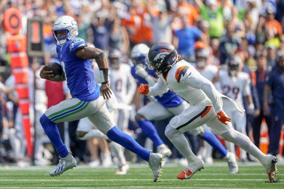 Seahawks quarterback Geno Smith runs past Broncos safety P.J. Locke to score a touchdown.