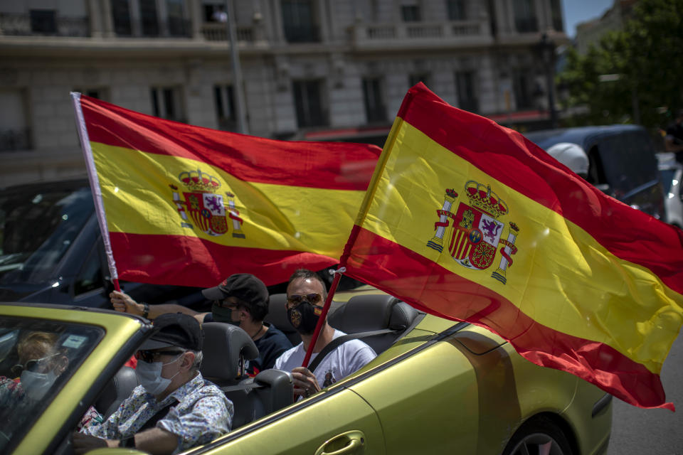 People wave Spanish flags in their cars during a drive-in protest organised by Spain's far-right Vox party against the Spanish government's handling of the nation's coronavirus outbreak in Barcelona, Spain, Saturday, May 23, 2020. Several thousand followers of Spain's far-right Vox party gathered Saturday in their cars and motorbikes in the center of Madrid and other Spanish cities to protest the Spanish government's handling of the nation's coronavirus crisis. (AP Photo/Emilio Morenatti)