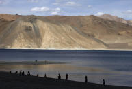 In this July 22, 2011 file photo, people stand by the banks of the Pangong Lake, near the India-China border in Ladakh, India.Indian officials say Indian and Chinese soldiers are in a bitter standoff in the remote and picturesque Ladakh region, with the two countries amassing soldiers and machinery near the tense frontier. The officials said the standoff began in early May when large contingents of Chinese soldiers entered deep inside Indian-controlled territory at three places in Ladakh, erecting tents and posts. (AP Photo/Channi Anand, File)