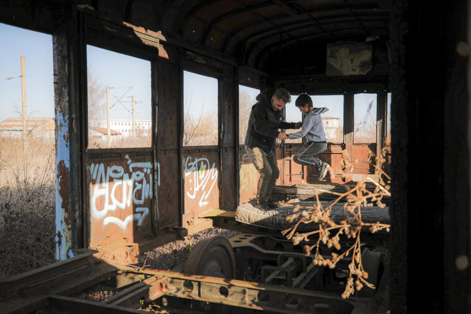 In this photo taken on Sunday, Dec. 15, 2019, Andrei, 19 years old, a youngster living in a transit home ran by Florin Catanescu, plays with a child in an abandoned train carriage, on the outskirts of Brasov, Romania. Thirty years after the 1989 death of Romania's communist-era dictator, the country is still grappling with the ugly legacy of its once-horrific orphanages. Now some of those who grew up abused and unloved in those failed institutions are turning their trauma into commitment. Florin Catanescu, who lived in an orphanage until 1997, now runs a transition home helping those leaving state care to have a better chance of leading meaningful lives. (AP Photo/Vadim Ghirda)
