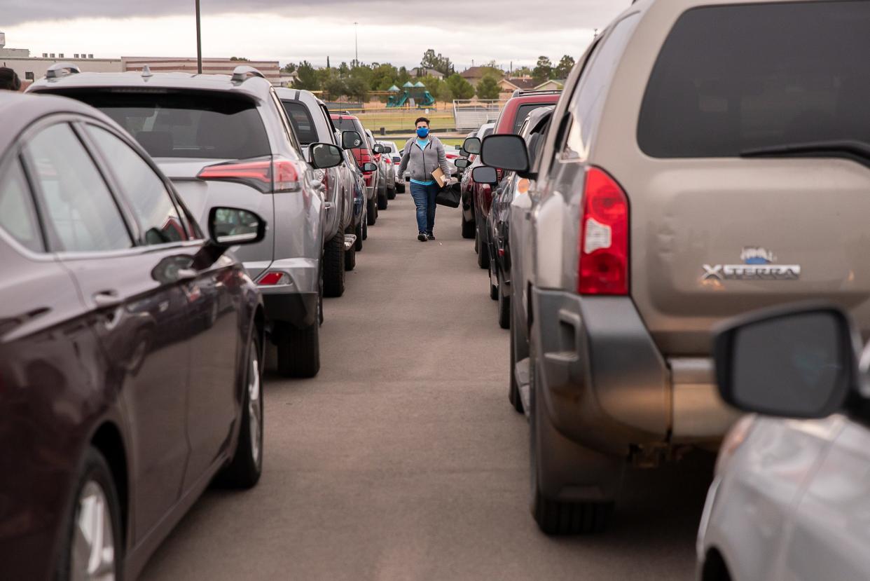 A Hope Border Institute volunteer walks from car to car to register voters at St. Mark Catholic Church in El Paso on Sept. 9, 2020.