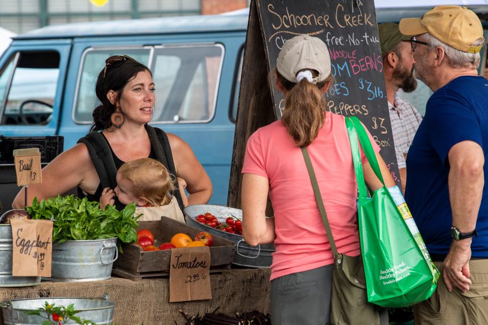 Sarah Dye talks with customers at the Schooner Creek Farm booth at the Farmer’s Market Saturday, August 17, 2019 at Showers Plaza. (Rich Janzaruk / Herald-Times)