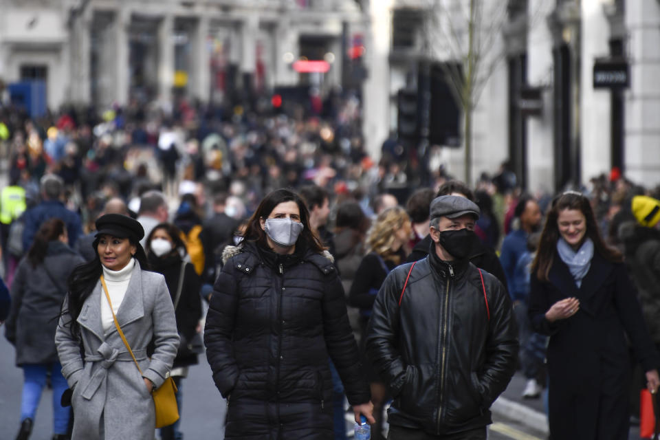 Shoppers walk wearing face masks and carrying shopping bags in Regent Street, after coronavirus restrictions were eased following the end of the second national lockdown in England, in London, Saturday, Dec. 5, 2020. (AP Photo/Alberto Pezzali)