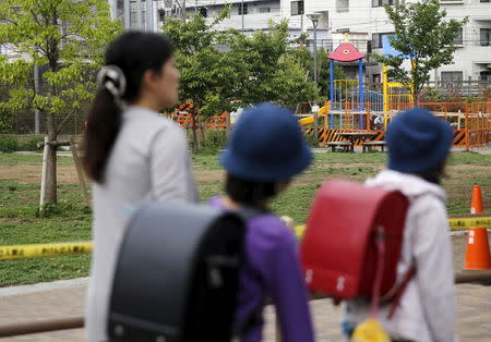 School children and a woman walk past the park where high radiation has been detected near a playground equipment (rear R) in Toshima ward, Tokyo April 24, 2015. REUTERS/Toru Hanai