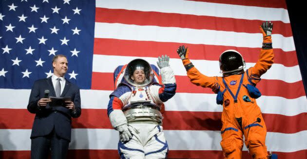 NASA Administrator Jim Bridenstine looks on as spacesuit engineer Kristine Davis models a red-white-and-blue prototype for NASA’s new Exploration Extravehicular Mobility Unit; and Dustin Gohmert, project manager for Orion Crew Survival Systems, gives a wave in the Orion Crew Survival System suit. (NASA Photo / Joel Kowsky)