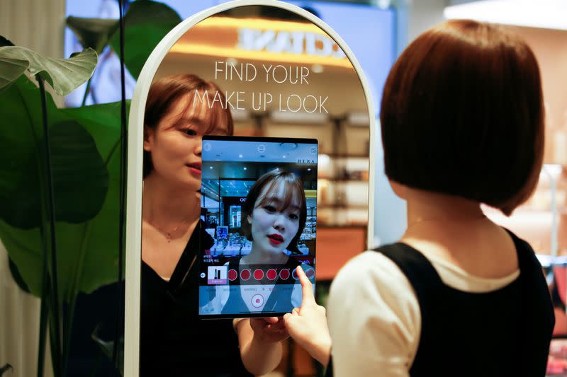 A woman shops using AR make up at a cosmetic shop in a department store in Seoul