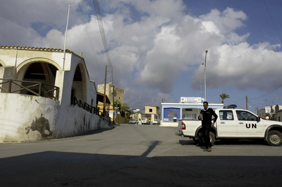 FILE - A UN police officer walks in front of a UN vehicle at the square of Pyla village at the UN buffer zone, outskirt of coastal city of Larnaca, Cyprus, Thursday, Jan. 8, 2009. Three United Nations soldiers had to be treated for minor injuries after angry Turkish Cypriots punched and kicked a group of peacekeepers who obstructed crews working on a road that would encroach on a U.N.-controlled buffer zone in ethnically divided Cyprus. The U.N. said Friday' s, Aug. 18, 2023, assault happened as peacekeepers stood in the way of work crews building a road to connect the village of Arsos in the breakaway Turkish Cypriot north with the mixed Greek Cypriot-Turkish Cypriot village of Pyla. (AP Photo/Petros Karadjias, File)