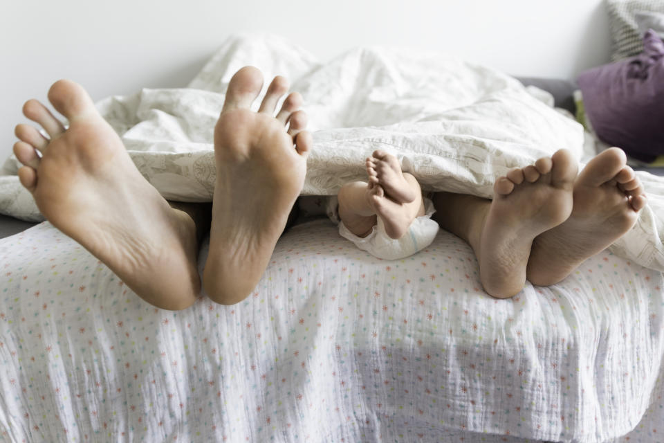 A couple with their baby in bed