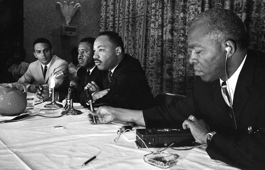 The Rev. Martin Luther King, center, speaks with the media at the Southern Christian Leadership Conference convention in Savannah, Ga., on Sept. 29, 1964. (Savannah Morning News via AP)