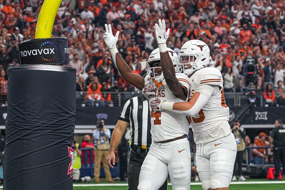 Texas running back CJ Baxter (4) and tight end Gunnar Helm (85) celebrate a touchdown by Baxter during the Big 12 Championship game against the Oklahoma State Cowboys at AT&T stadium on Saturday, Dec. 2, 2023 in Arlington.