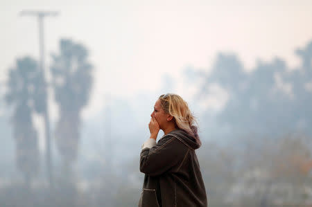 A woman reacts as the Woolsey Fire burns in Malibu, California, U.S. November 9, 2018. The fire destroyed dozens of structures, forced thousands of evacuations and closed a major freeway. REUTERS/Eric Thayer