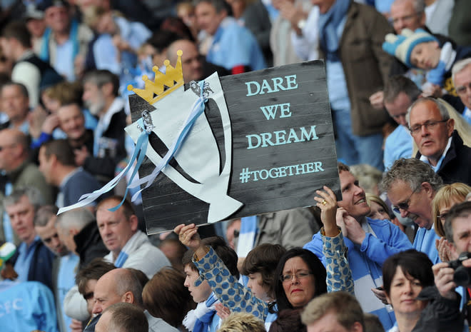 Manchester City supporters hold a home-made trophy banner aloft before the English Premier League football match between Manchester City and Queens Park Rangers at The Etihad stadium in Manchester, north-west England on May 13, 2012. AFP PHOTO/PAUL ELLIS RESTRICTED TO EDITORIAL USE. No use with unauthorized audio, video, data, fixture lists, club/league logos or “live” services. Online in-match use limited to 45 images, no video emulation. No use in betting, games or single club/league/player publications.PAUL ELLIS/AFP/GettyImages