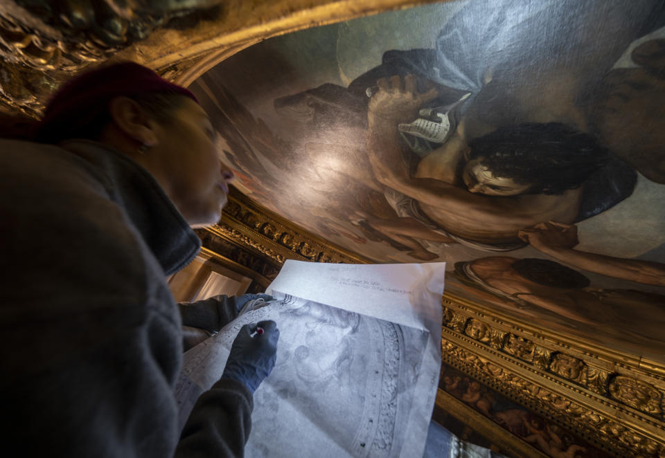 La restauradora Romana Albini señala los signos de decadencia de una obra de arte dentro del Palacio Ducal de Venecia, el miércoles 7 de diciembre de 2022. (AP Foto/Domenico Stinellis)