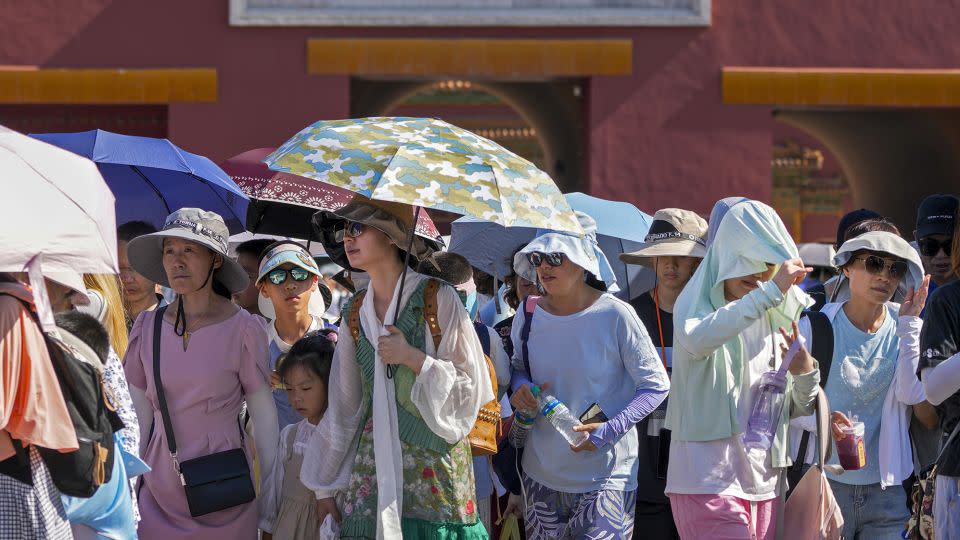 Visitors wear sun hats and carry umbrellas as at the Forbidden City on a hot day in Beijing, on June 29. - Andy Wong/AP