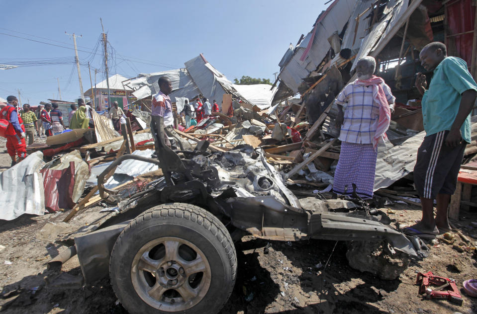 Somali men stand amidst the wreckage after a car bomb attack at a busy junction in the Wadajir district of the capital Mogadishu, Somalia, Monday, Nov. 26, 2018. Somalia was hit by two violent attacks Monday, one killing an Islamic cleric in the northern city of Galkayo, and a second killing at least six people in a car bomb blast in Mogadishu, police said. (AP Photo/Farah Abdi Warsameh)