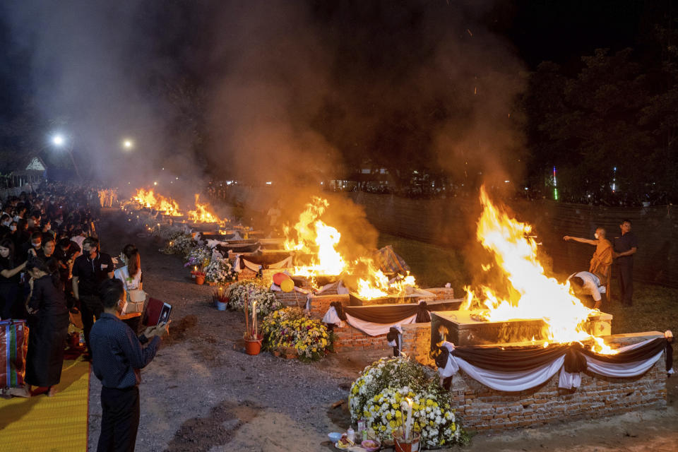 Fires are seen through a privacy net as funeral pyres cremate those who died in the day care center attack at Wat Rat Samakee temple in Uthai Sawan, northeastern Thailand, Tuesday, Oct. 11, 2022. A former police officer burst into a day care center in northeastern Thailand on Thursday, killing dozens of preschoolers and teachers before shooting more people as he fled (AP Photo/Wason Wanichakorn)