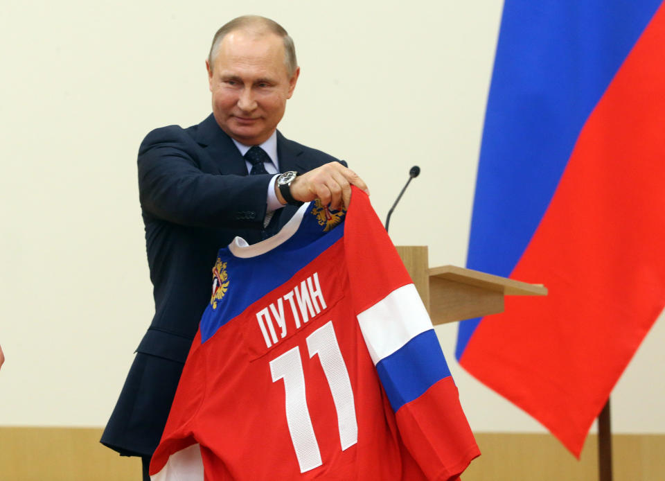 NOVO-OGARYOVO, RUSSIA - JANUARY 31: (RUSSIA OUT) Russian President Vladimir Putin holds up a uniform during his meeting with Olympic athletes who will take part in the upcoming 2018 Pyeongchang Winter Olympic Games, on January 31, 2018 at Novo-Ogaryovo State Residence, 10 km. west of Moscow, Russia. (Photo by Mikhail Svetlov/Getty Images)