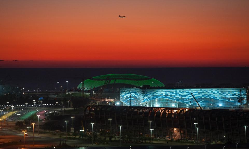 FILE - This Oct. 24, 2013 file photo shows the illuminated Olympic Bolshoy stadium, in the background, and Iceberg stadium, the location for figure skating and short track speed skating events during the 2014 Olympic Games, in the Olympic park in the coastal cluster in the Black Sea resort of Sochi, Russia. (AP Photo/Lesya Polyakova, File)