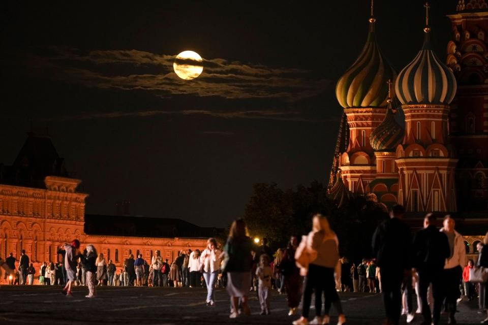 The super blue moon sets behind a historical building and the St. Basil's Cathedral, right, as people walk in Red Square in Moscow, Russia, on Aug. 30, 2023.<span class="copyright">Alexander Zemlianichenko—AP</span>