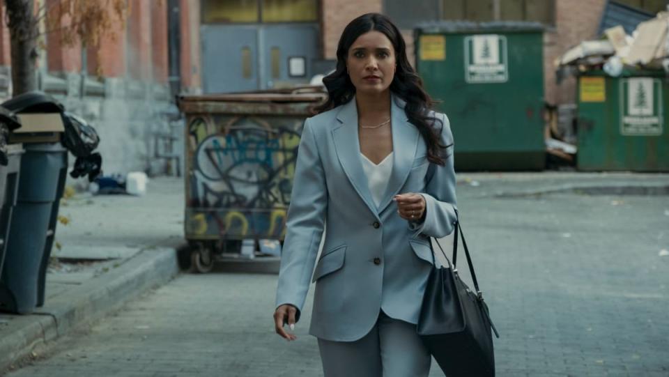 Dean shetty walks down an alleyway wearing a blue suit in Gen V