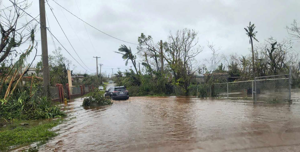 In this photo provided by Chris Leavitt, vehicles make their way through a flooded street Thursday, May 25, 2023, in Yigo, Guam, after Typhoon Mawar passed over the island. (Chris Leavitt via AP)