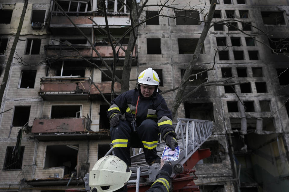 Ukrainian firefighters hold a photograph, found in the rubble, as they work in a resident building after it was hit by artillery shelling in Kyiv, Ukraine, Monday, March 14, 2022. (AP Photo/Vadim Ghirda)