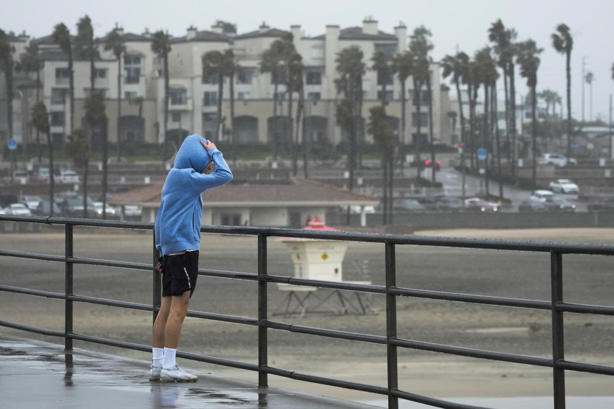 A man looks out from the Huntington Beach Pier on Friday, Feb. 24, 2023, in Huntington Beach, Calif. California and other parts of the West faced heavy snow and rain Friday from the latest winter storm to pound the U.S. (AP Photo/Ashley Landis)