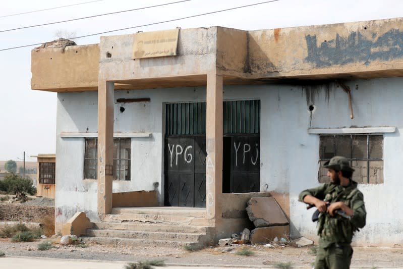 FILE PHOTO: A Turkey-backed Syrian rebel fighter stands near a former YPG office at the entrance of Tel Abyad