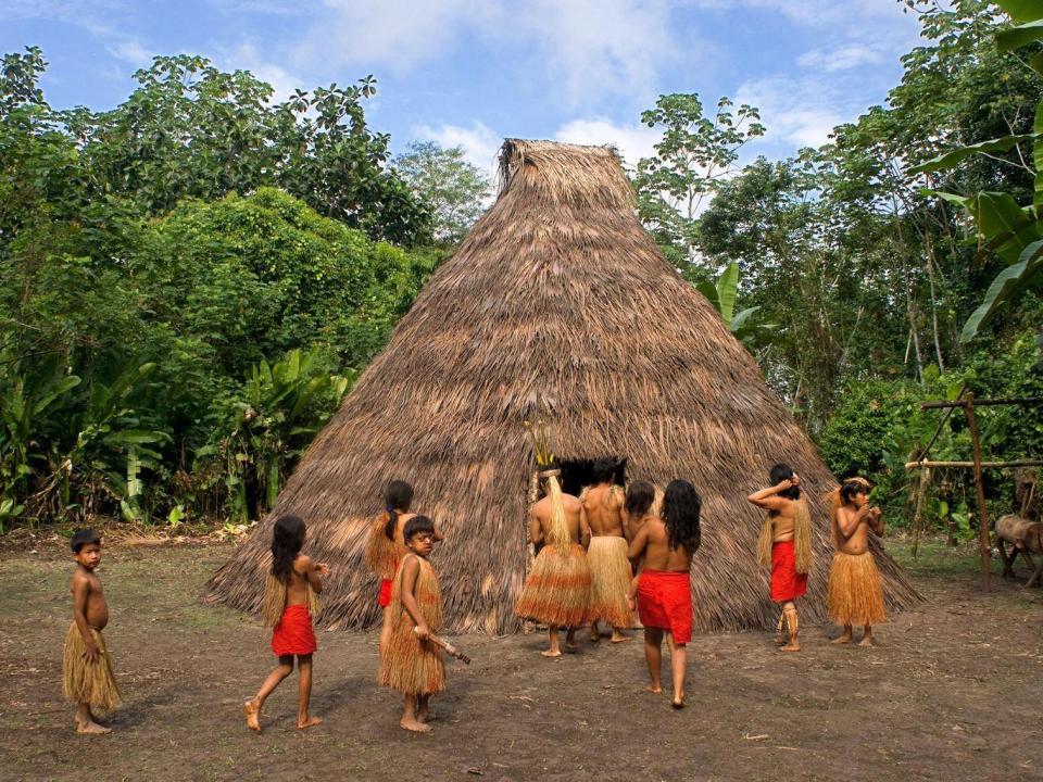 Yagua tribe next to their Maloca, a traditional house with thatched roof, in Iquitos, Amazonian, Peru. (Alamy)