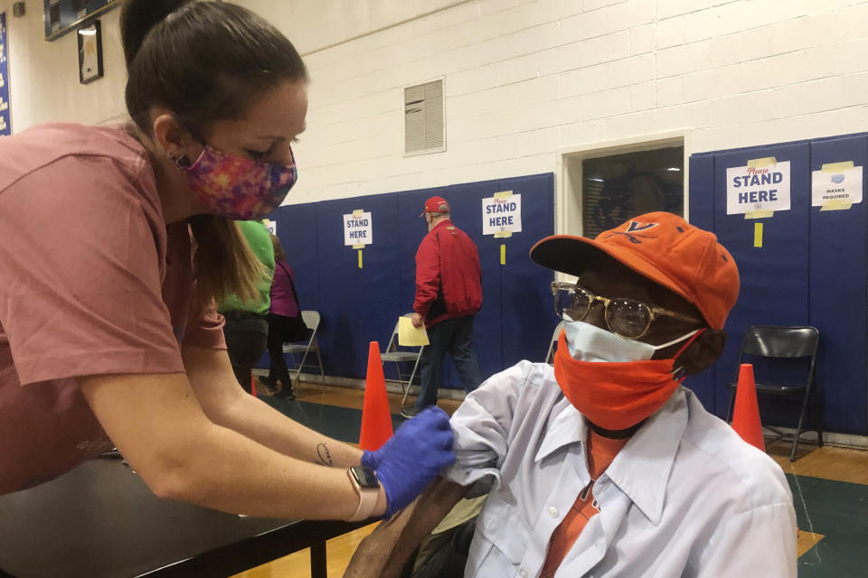 Debbie Monahan, a school nurse, pulls down Charles Robbins' sleeve after giving him his second shot of the coronavirus vaccine at Surry County High School in Dendron, Va., on Saturday Feb. 27, 2021. Getting the coronavirus vaccine has been a challenge for rural counties in the U.S. that lack medical facilities such as a pharmacy or a well-equipped doctor's office. (AP Photo/Ben Finley)