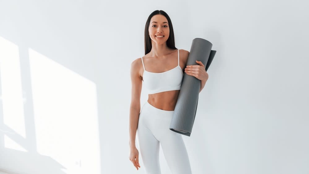  A photo of a woman holding an exercise mat. 