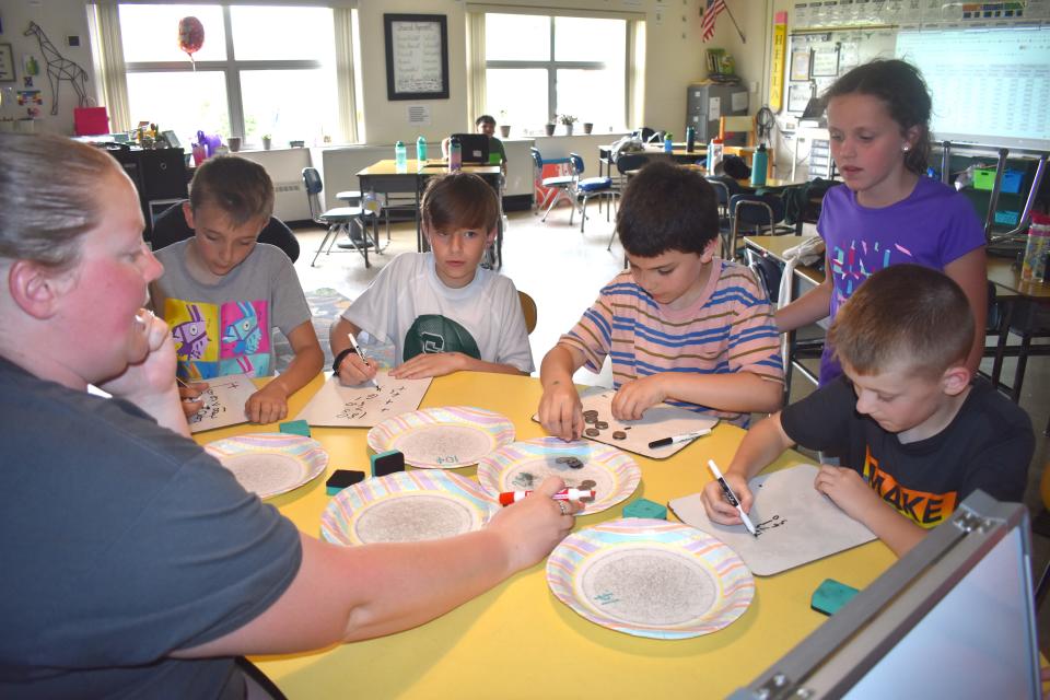 Fourth grade students at Ruth McGregor Elementary School in Sand Creek, from left, Caden Brewer, Emerson Walsh, Damien Salerno, Grace Hassenzahl and Jackson Smith, count up coins with the assistance of teacher Caitlyn Hella Friday during the final day of the elementary school's Money Wars fundraiser.