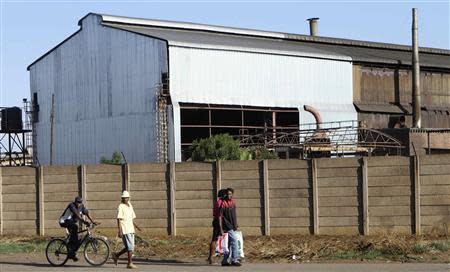 Zimbabweans walk past a dilapidated tube and pipe company in the industrial area of Workington, Harare November 14, 2013. REUTERS/Philimon Bulawayo