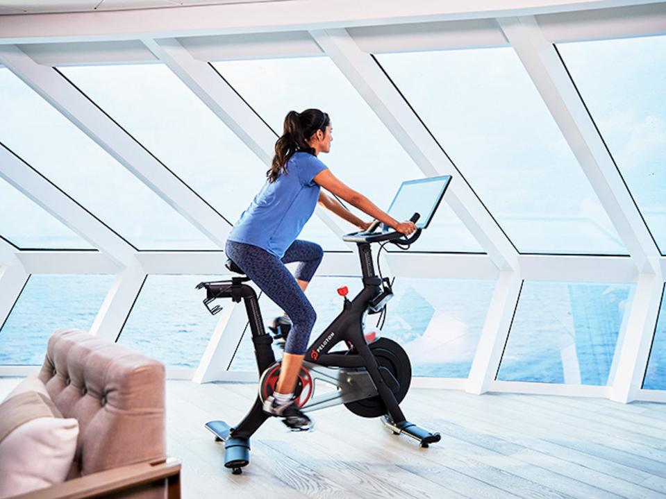 a rendering of a woman riding a Peloton while facing windows looking out into the ocean