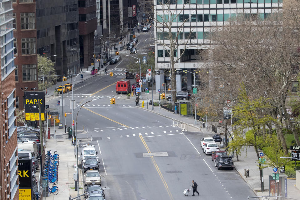 A pedestrian walks across Water Street empty of traffic, Friday, April 10, 2020, in the financial district of New York. The new coronavirus causes mild or moderate symptoms for most people, but for some, especially older adults and people with existing health problems, it can cause more severe illness or death. (AP Photo/Mary Altaffer)